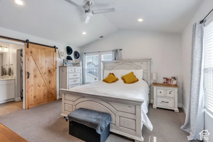 Vaulted ceiling, sliding wood barn door, recessed lighting, and ceiling fan