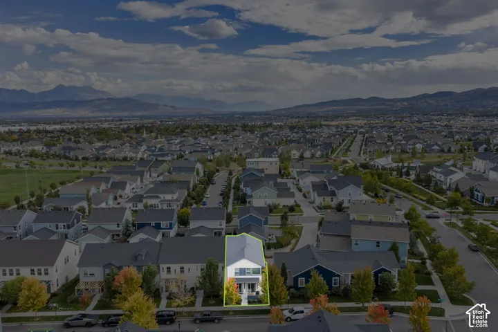 Aerial view of a two-story residence featuring a gray gabled roof, white exterior siding, and a mountain backdrop