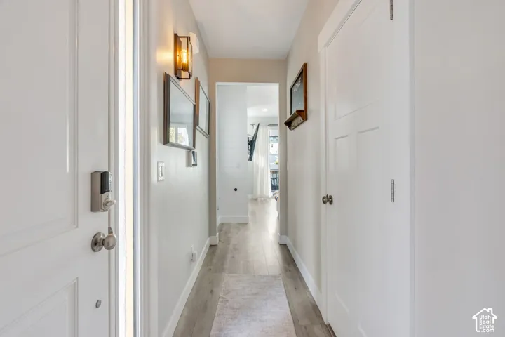 Hallway featuring wood-finish flooring, white paneled doors, and wall-mounted sconce lighting