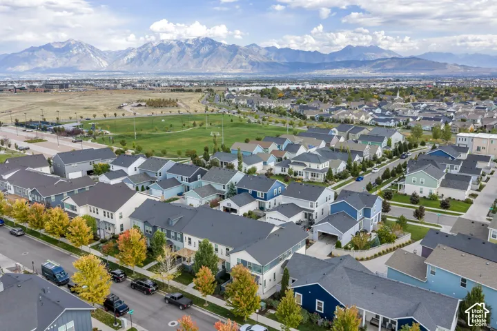 Aerial perspective featuring a residential community with paved streets, multi-level homes, and a mountain range backdrop