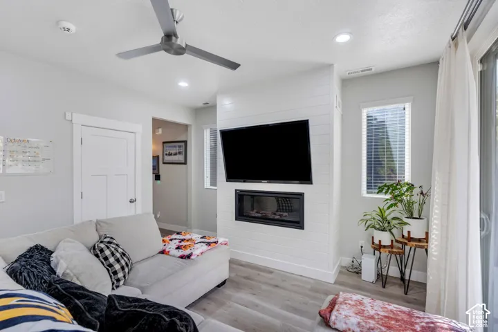 Shiplap accent wall with a built-in electric fireplace, wood-finish flooring, recessed lighting, and a modern ceiling fan