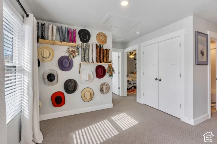 Neutral carpeting, double-door closet with shaker-style panels, recessed ceiling lighting, and natural wood-finish wall shelving