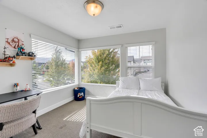 Neutral wall tones, wall-to-wall carpeting, and a wraparound window configuration featuring horizontal blinds and a flush-mount ceiling light fixture