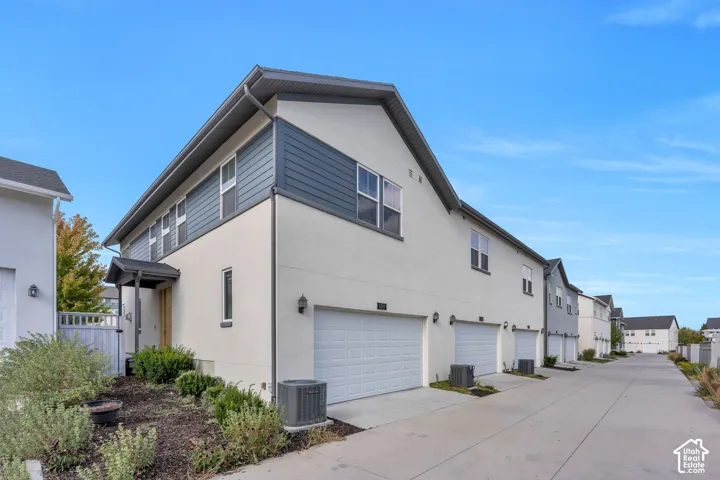 Multi-unit exterior featuring a mix of stucco and horizontal lap siding, dual-pitched roofline, multi-car garage access, and private driveway