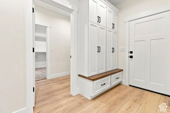 Built-in cabinetry featuring shaker-style doors, matte black hardware, and a wood-finish bench seat with integrated storage drawers, complemented by wood-finish flooring and a craftsman-style door