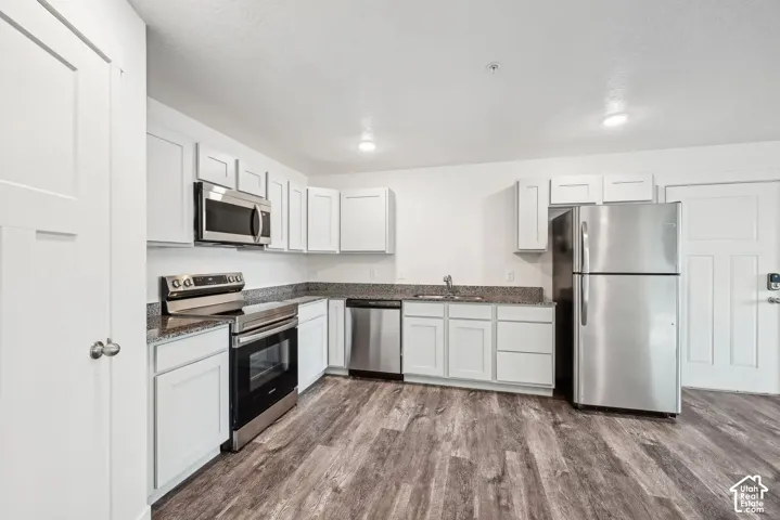 Kitchen featuring white shaker-style cabinetry, granite countertops, stainless steel appliances, and LVP flooring
