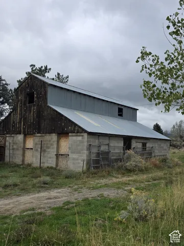 Outbuilding featuring concrete block construction, vertical wood siding, and a metal roof