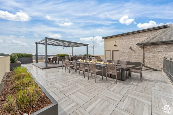 Expansive rooftop terrace featuring large-format wood-finish tile flooring, a metal pergola, a built-in linear gas fire pit, and raised garden planters