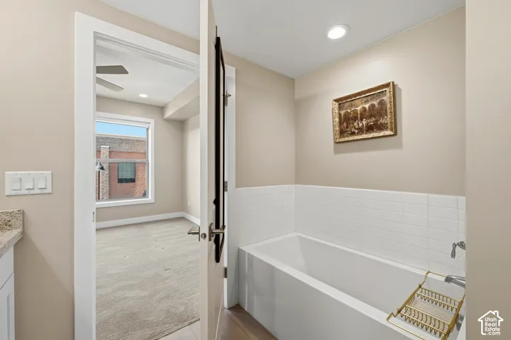 Bathroom featuring a white rectangular drop-in soaking tub, white square-tile tub surround, and recessed ceiling lighting