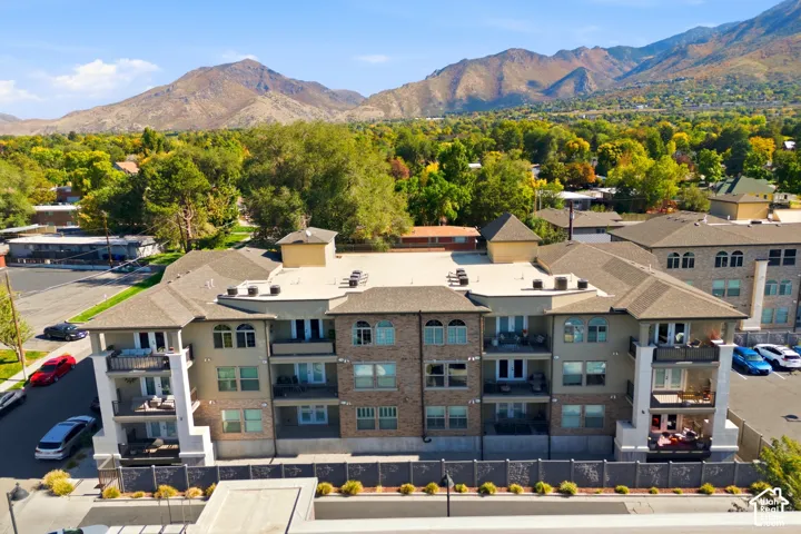 Multi-level residential building featuring stone veneer facade, shingled roofing, private balconies, and proximity to mountain range