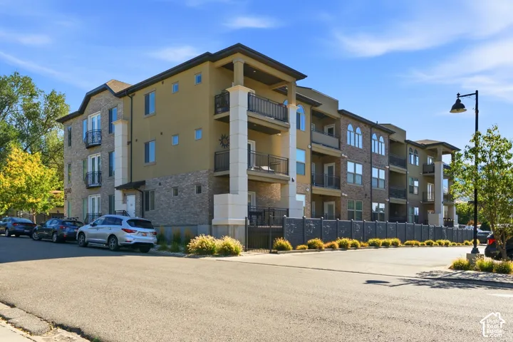 Multi-level exterior featuring stone veneer siding, stucco accents, private balconies with metal railings, and structural columns