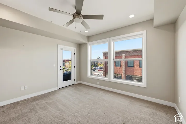 Neutral-toned interior featuring recessed lighting, a brushed-nickel ceiling fan, wall-to-wall carpeting, and a glass-paneled door