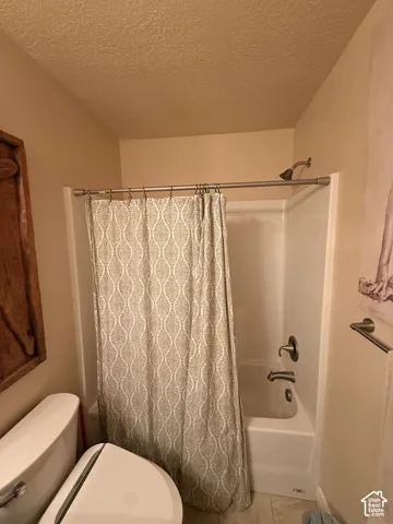 Full-size tub and shower combination featuring a white surround, brushed nickel plumbing fixtures, and a wall-mounted towel bar