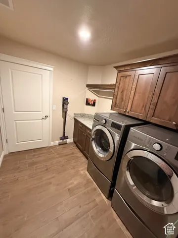 Laundry area featuring wood-finish tile flooring, stone-surface countertop, and stained wood cabinetry with upper and lower storage