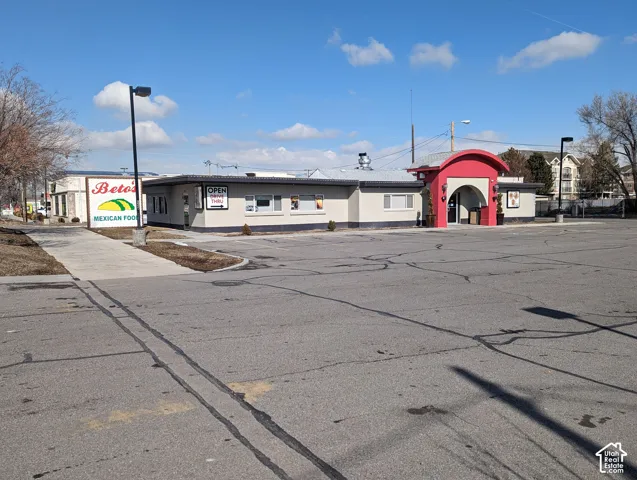 Commercial property featuring a paved asphalt parking lot, drive-thru access, exterior signage, and a prominent arched entryway
