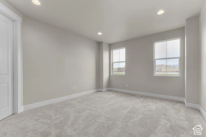 Neutral interior space featuring wall-to-wall carpeting, recessed ceiling lighting, and dual windows with multi-pane grid detailing