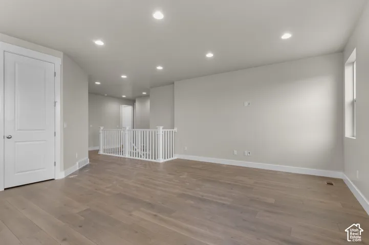 Open-concept interior featuring wood-finish flooring, recessed lighting, and white wooden stair railing