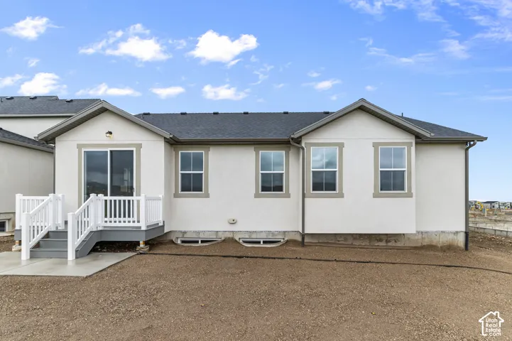 Exterior featuring light-toned stucco siding, asphalt shingle roof, double-hung windows with trim detailing, and a raised composite deck with white railings