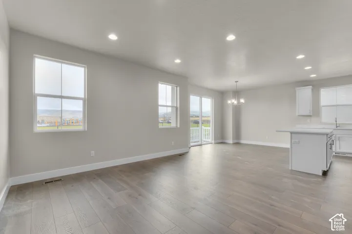 Open-concept interior featuring wood-finish flooring, recessed lighting, white cabinetry, a kitchen island, and glass sliding doors