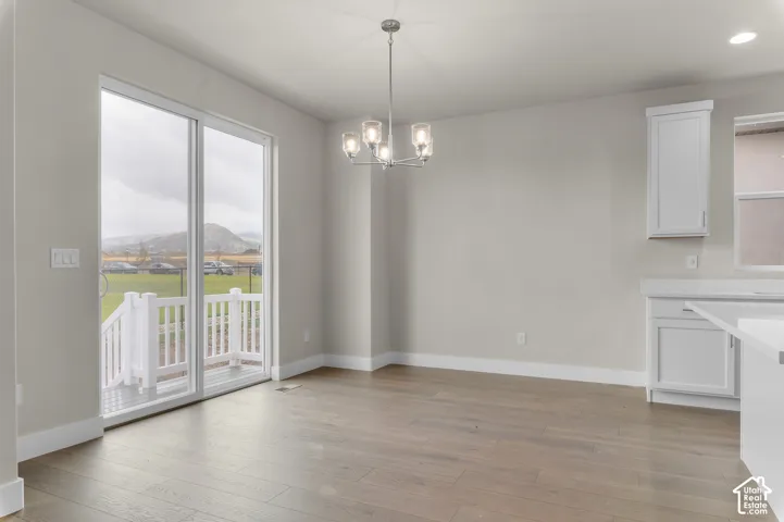 Wood-finish flooring, glass sliding door, multi-arm chandelier, and white cabinetry