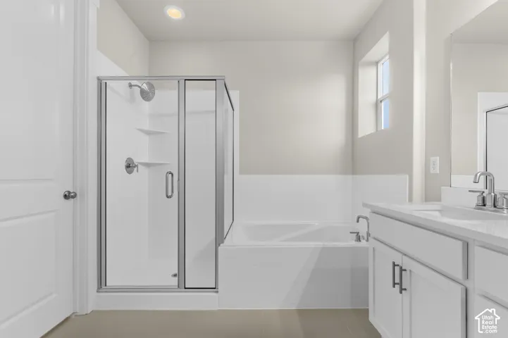 Bathroom featuring a separate glass-enclosed shower, soaking tub, vanity with a white countertop, and recessed lighting