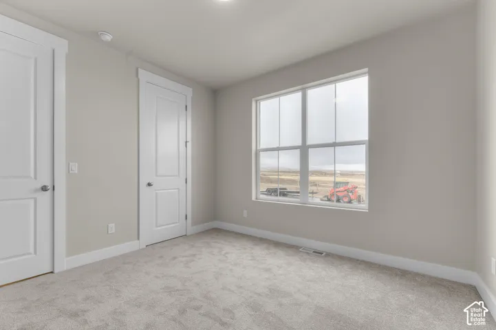 Interior room featuring neutral wall paint, wall-to-wall carpeting, two white paneled doors with matching trim, and a multi-pane window