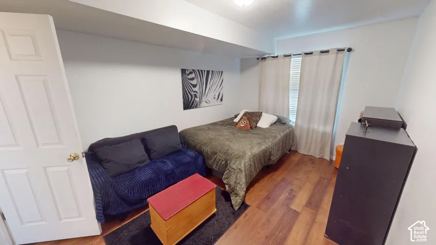 Interior room featuring wood-finish flooring, a neutral color palette, and a single-window configuration with a rod-mounted curtain system