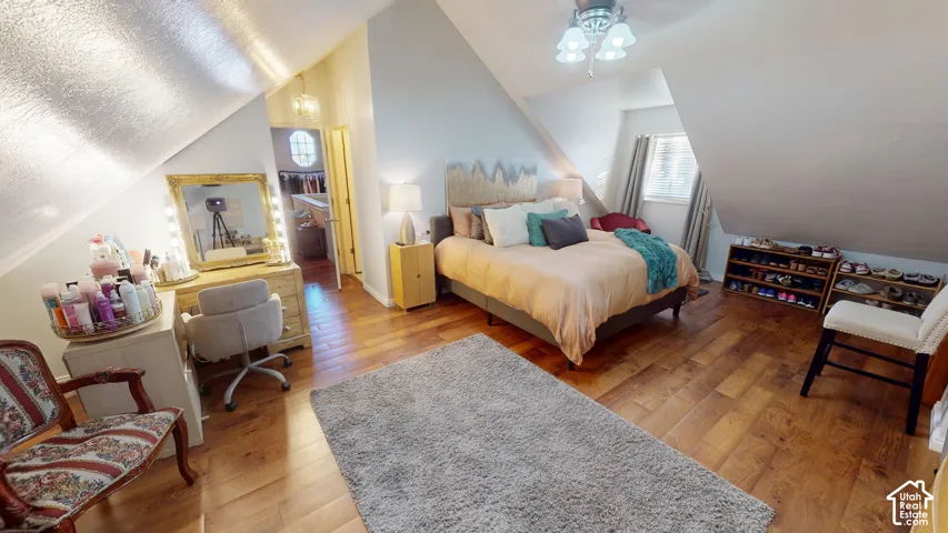 Vaulted ceilings, wood-finish flooring, and a multi-arm ceiling light fixture
