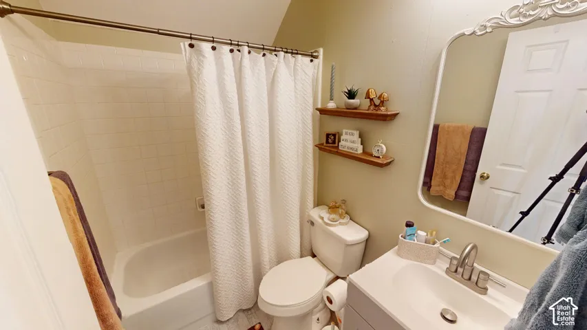 Full bathroom featuring a tub-shower combination with white tile surround, built-in wooden shelving, a vanity with an integrated sink, and an arched wall-mounted mirror