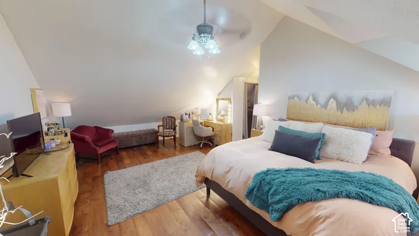 Vaulted ceiling with angled architectural lines, wood-finish flooring, and a multi-light ceiling fan