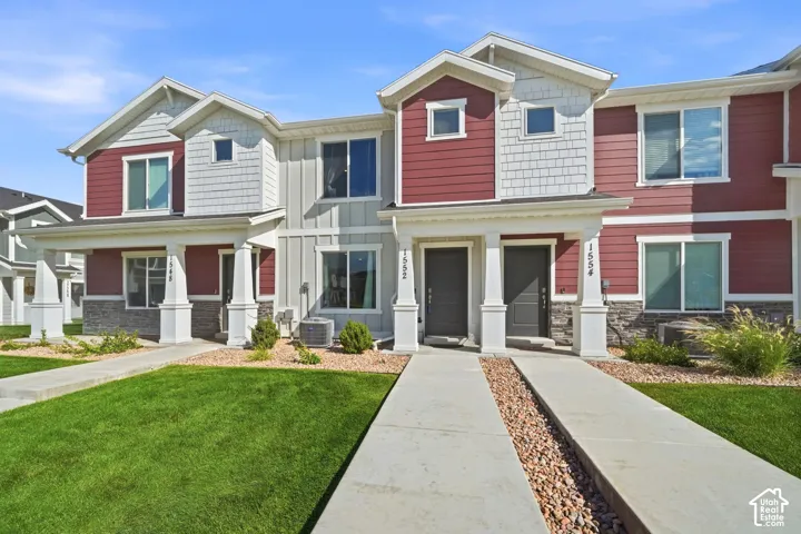 Red siding and light gray siding exterior with stone accents, covered entryways, multiple windows, and a manicured lawn
