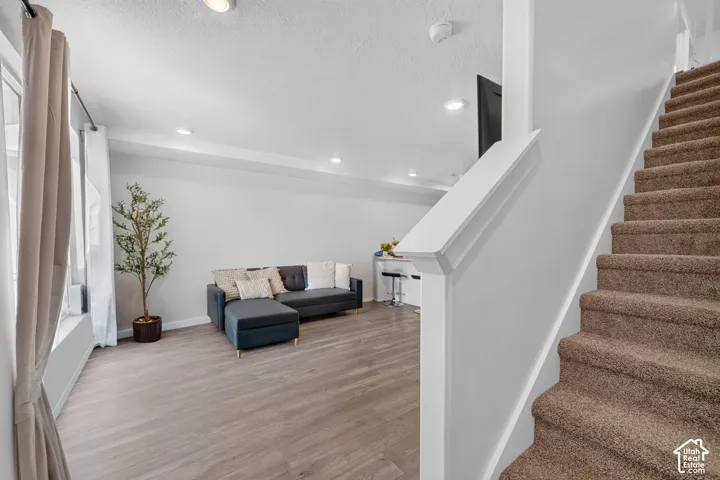 Recessed lighting illuminates the open-concept living space with wood-finish flooring