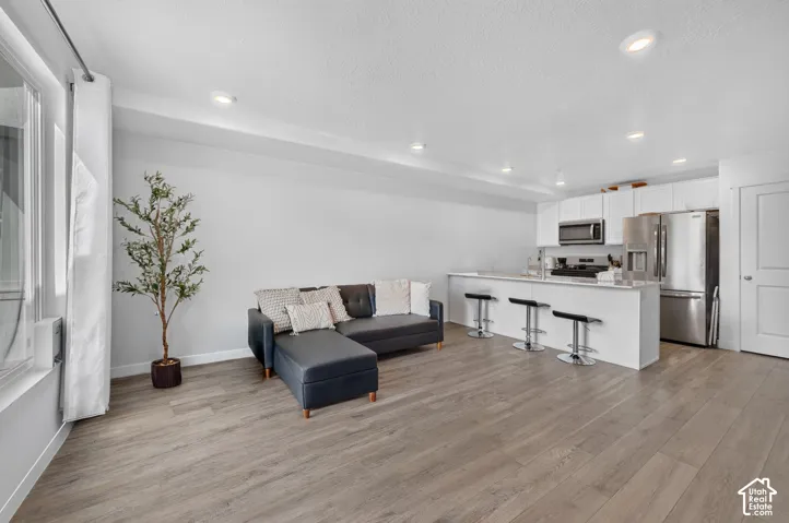 Open-concept living space with wood-finish flooring, recessed lighting, and a window for natural light