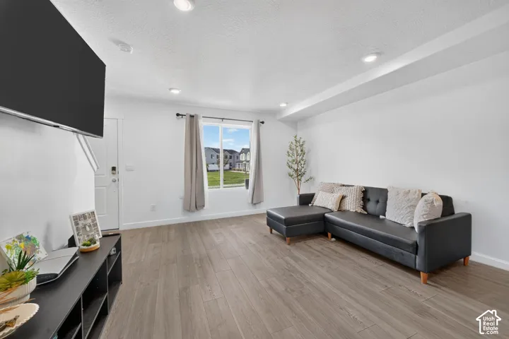 Recessed lighting, wood-finish flooring, white walls, and a large window