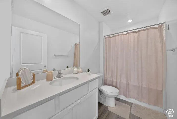 Bathroom featuring a single vanity with an integrated sink, a rectangular mirror, recessed lighting, and a full bathtub with a shower curtain