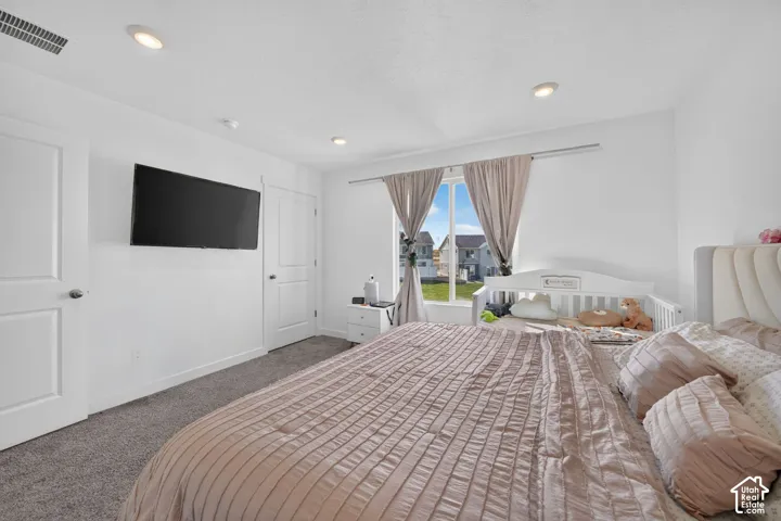Wall-mounted television with recessed lighting, soft gray carpeting, and white paneled doors