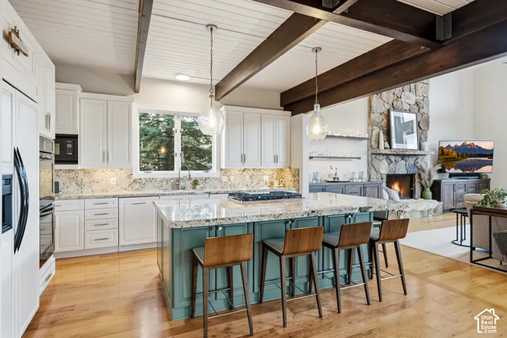 Vaulted tongue-and-groove ceiling with exposed wood beams, bright kitchen cabinetry, granite countertops, and wood-finish flooring