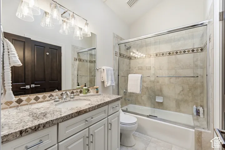 Vanity with integrated sink and stone countertop, polished chrome faucet, white cabinetry, and a full wall mirror