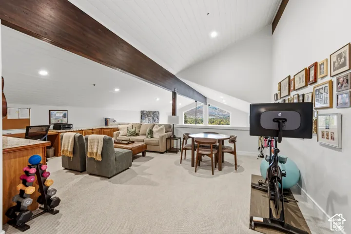 Spacious loft area featuring a vaulted ceiling with exposed wood beams, recessed lighting, and dormer windows