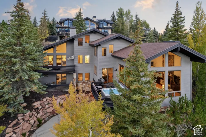 Multi-level residence featuring a hot tub, multiple balconies, a stone retaining wall, and extensive window walls