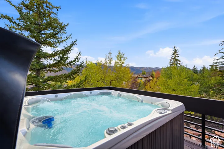 Outdoor spa with a multi-jet system, situated on a wood-finish deck with a dark railing