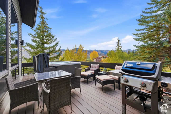 Expansive outdoor deck featuring wood-finish flooring, a built-in hot tub, and a durable metal railing