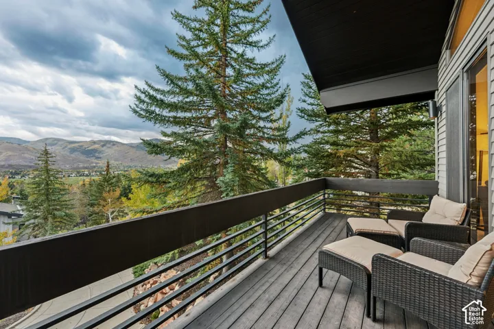 Spacious balcony featuring wood-finish decking, horizontal metal railings, and an exterior wall with siding
