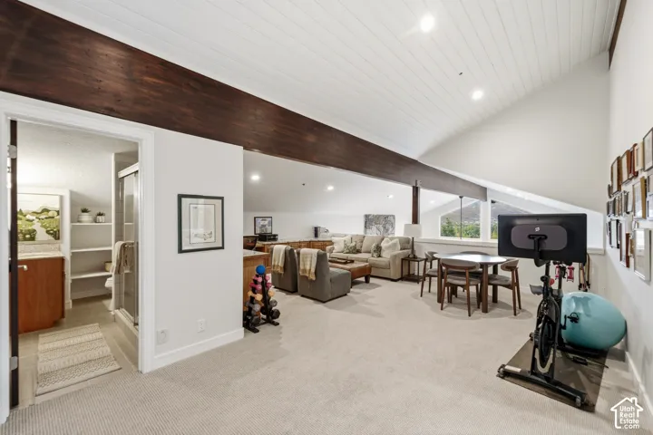 Vaulted ceiling with white plank finish, exposed dark wood beams, recessed lighting, and a full bathroom with a glass-enclosed shower
