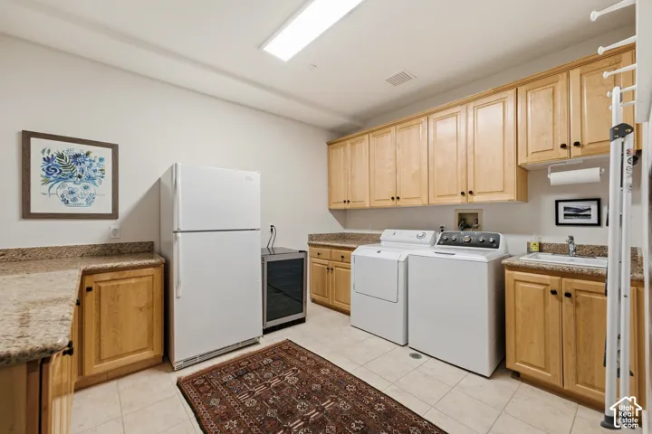 Light wood cabinetry, granite-style countertops, tile flooring, built-in utility sink, and recessed lighting