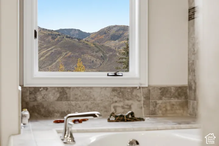 Built-in bathtub with a polished chrome faucet, white countertop, and tiled backsplash
