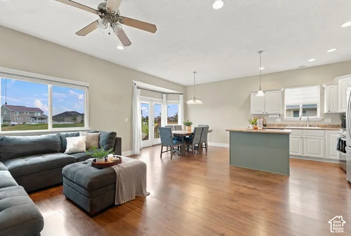 Open-concept interior featuring wood-finish flooring, recessed lighting, white cabinetry, a center island, and a double-door exit leading to an exterior deck