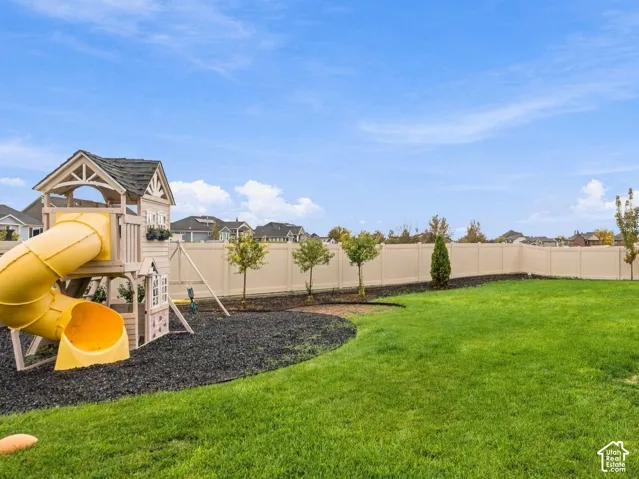 Expansive backyard featuring a level lawn, perimeter privacy fencing, crushed stone landscaping, and a multi-tiered wooden deck