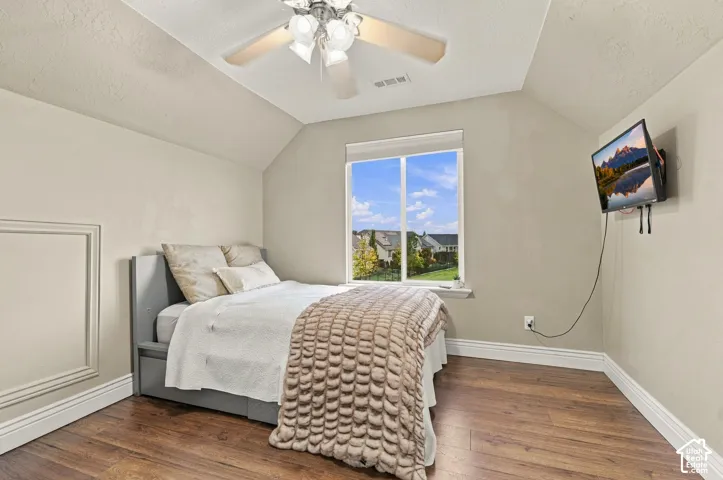 Wood-finish flooring, vaulted ceilings, multi-light ceiling fan, and large picture window