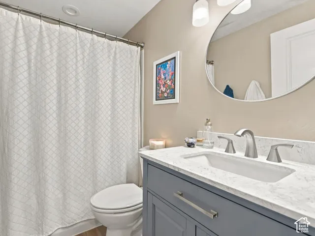 Bathroom featuring a charcoal vanity with a white-veined stone countertop, an integrated rectangular sink, a brushed-nickel widespread faucet, and an oval wall-mounted mirror